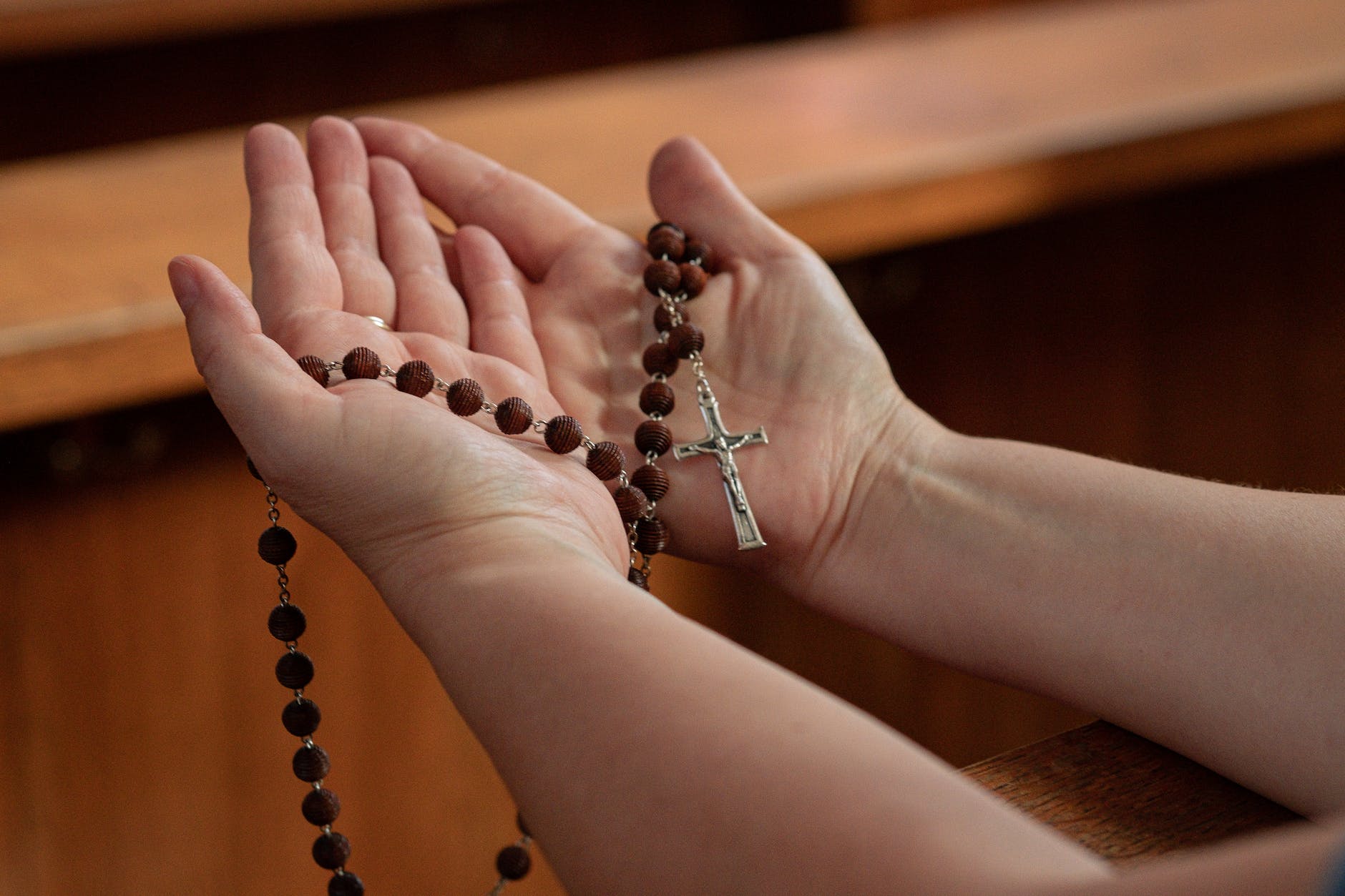 person holding a silver and brown beaded rosary