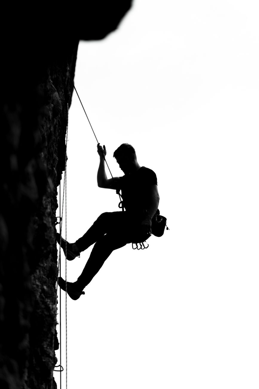 silhouette of man rock climbing