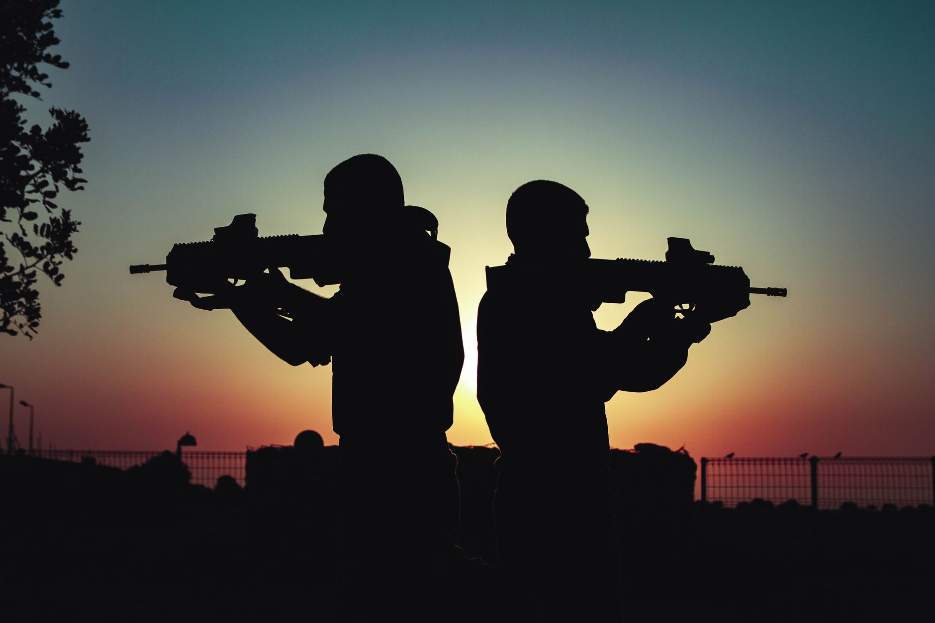 silhouette of men holding guns